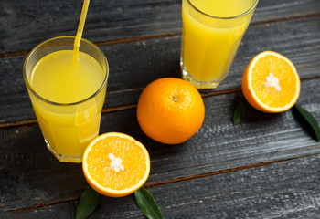 Fresh delicious orange juice. Cut pieces of orange and a glass on a wooden table