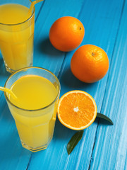 Fresh delicious orange juice. Cut pieces of orange and a glass on a wooden table