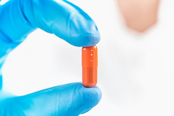 Scientist’s Hand in a Glove Holding an Orange Pill