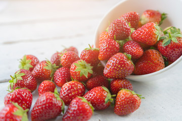 Red strawberry heap on white wood table.