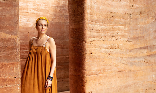 Portrait of beautiful Caucasian woman standing by the rammed earth walls.