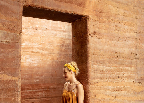 Portrait of pretty Caucasian woman standing by the rammed earth walls.