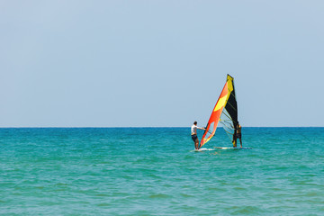 Windsurfing on the background of the sea landscape and clear sky.Two windsurfers men go in for sports, copy space.