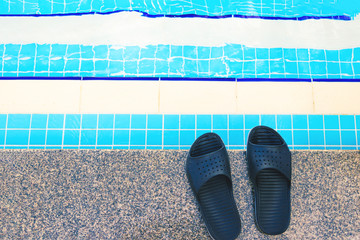 Summer background with slippers for the pool black color near the pool, steps for the descent into...