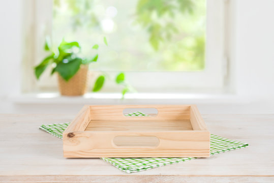 Empty wooden tray on table over blurred summer window background