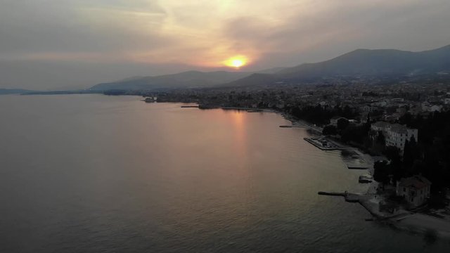 Steady drone shot of the glorious Kastela bay in Croatia with the Dalmatian mountain range in clear view in the background. Forward motion heading towards the sunset providing beautiful colours.