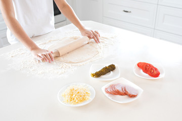 top view of a child making pizza dough on a light tabletop