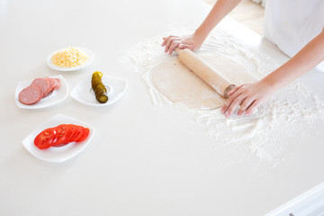 Obraz na płótnie Canvas top view of a child making pizza dough on a light tabletop