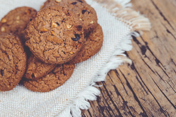 Fototapeta premium Close up of a group Chocolate chip cookies many stacked on apron sackcloth dark old rustic wooden plank table with Leave Copy space place for text. freshly baked. dessert