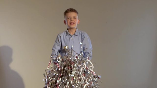 Slow motion of little fellow jumping and throwing up tinsel.