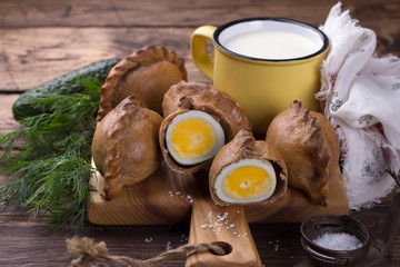 Russian traditional rye pies with egg, kokurki, on a wooden table