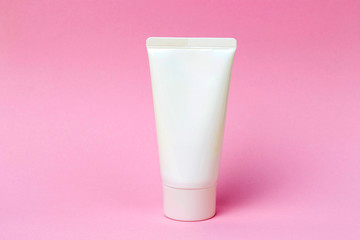 Tube with cream on a pink background, front view, cosmetics care concept
