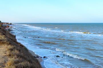 Top view on the sea and the waves crashing on the shore in the sunlight. Beach on the coast.