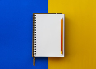 Blank white notepad with pencil isolated on two tone yellow and blue background. - 260956517