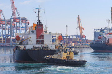 Tugboat at the bow of cargo ship , assisting the vessel to maneuver in Sea Port of Odessa, Ukraine