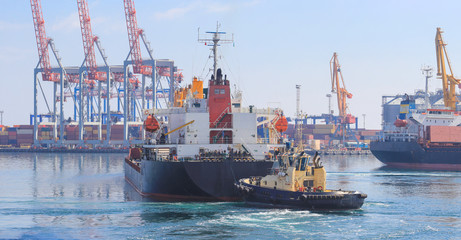 Tugboat at the bow of cargo ship , assisting the vessel to maneuver in Sea Port of Odessa, Ukraine