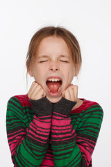 Portrait of a screaming 8-year-old girl in a sweater in crimson and green stripes