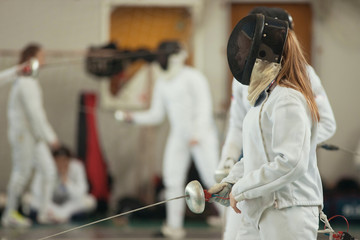 A girl with long hair having fencing duel on tournament.