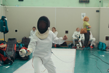 A girl fencer having fencing duel on tournament