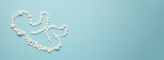 Silhouette of a human embryo (child) from white tablets on a blue background. Treatment of newborns, medical care.