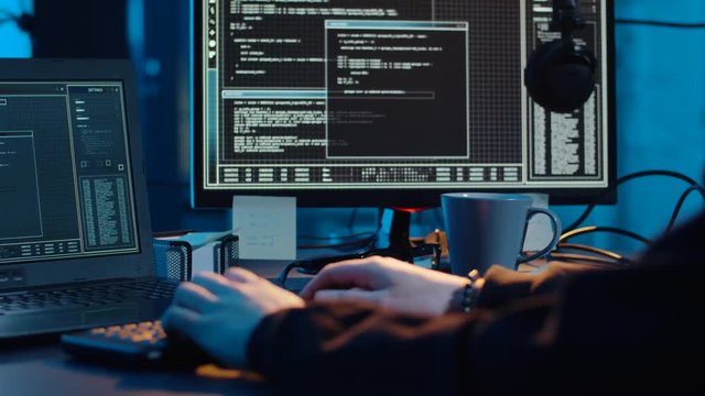 cybercrime, hacking and technology concept - asian male hacker writing code or using computer virus program for cyber attack and drinking coffee in dark room at night