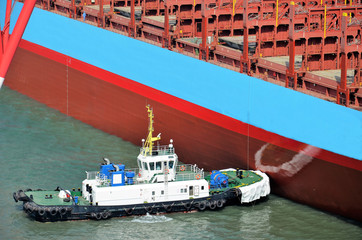 Tugboat assisting to the container ship in port.