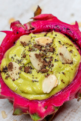 Green avocado smoothie in dragon fruit skin with almond flakes and chia seeds for breakfast , close up. The concept of healthy eating, superfood