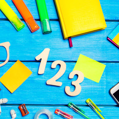 school supplies in the school desk, stationery, school concept, blue background, creative chaos, space for text, markers, pens, notepads, stickers. wooden numbers 1, 2, 3