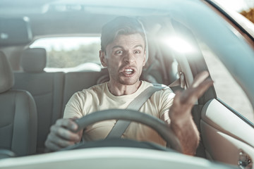 Angry brunette man using bad language while driving