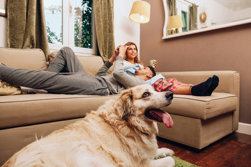 Young smiling couple together on sofa whit their dog