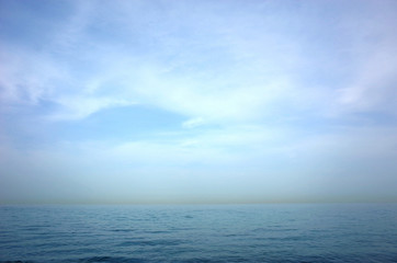 Blue seascape of Gulf of Oman seen from Arabian peninsula with yellow line of sandstorm over Iran