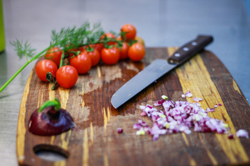 Girl chef slicing vegetables. Tomatoes, parsley, onion, apple. Wooden board for slicing vegetables.Curtain processes
