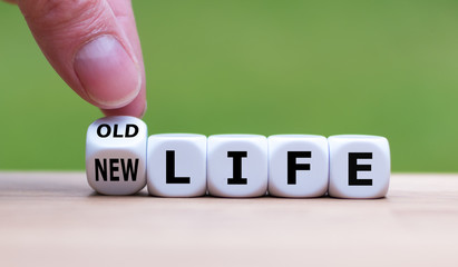 Hand turns a dice and changes the expression "old life" to "new life".