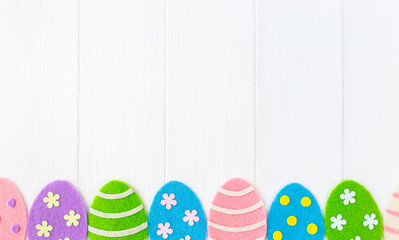 Closeup top view photo of cute diy colorful pastel eggs decorated with dots, stripes and flowers isolated on white painted wooden background. Happy Easter holiday greeting card with copyspace.