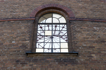 Old arched window on dark brick wall. Architecture
