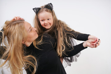 cute kind caucasian blonde mom and daughter posing on white background. a parent and a child experience love and hug.