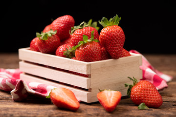 Strawberries in a basket on old wooden table
