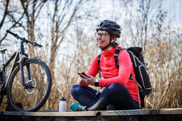 female cyclist listens to music while relaxing on the bridge in the forest
