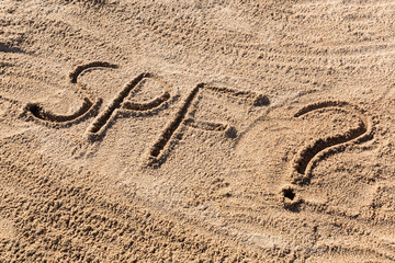 Fototapeta na wymiar Sun protect factor concept. SPF word written on the beach with question mark