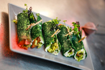 The girl's chef is preparing green crepe roles with basil cheese and stuffed. Green cheese. Cooking in the kitchen