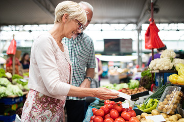 Picture of mature woman at marketplace buying vegetables