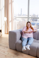 Obraz premium Positive cheerful plump woman resting at home