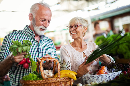 Shopping, food, sale, consumerism and people concept - happy senior couple buying fresh food