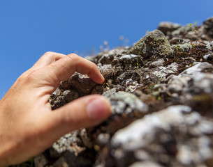 Hand on the stone rock in the mountains as background
