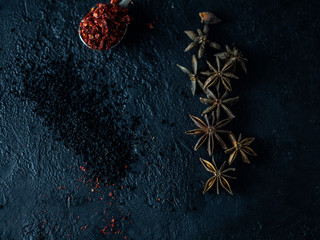 A set of spices on a dark stone background.