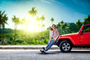 Red summer car on road and two lovers. Blurred background of palms and sunset time. Free space for your decoration. 