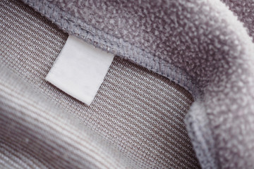 blank white clothing label on gray fabric texture background