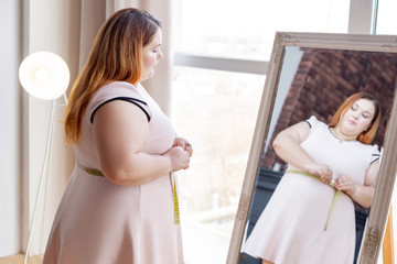 Pleasant plump woman looking into the mirror