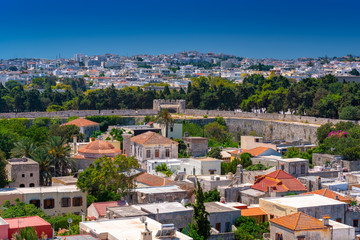 Fototapeta na wymiar Panoramic view of the Rhodes medieval old city surrounded by ancient stone defensive walls, with the new town and Acropolis in the background. Popular summer holiday destination in the Greece.