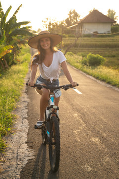 Woman is riding bicycle by narrow country road